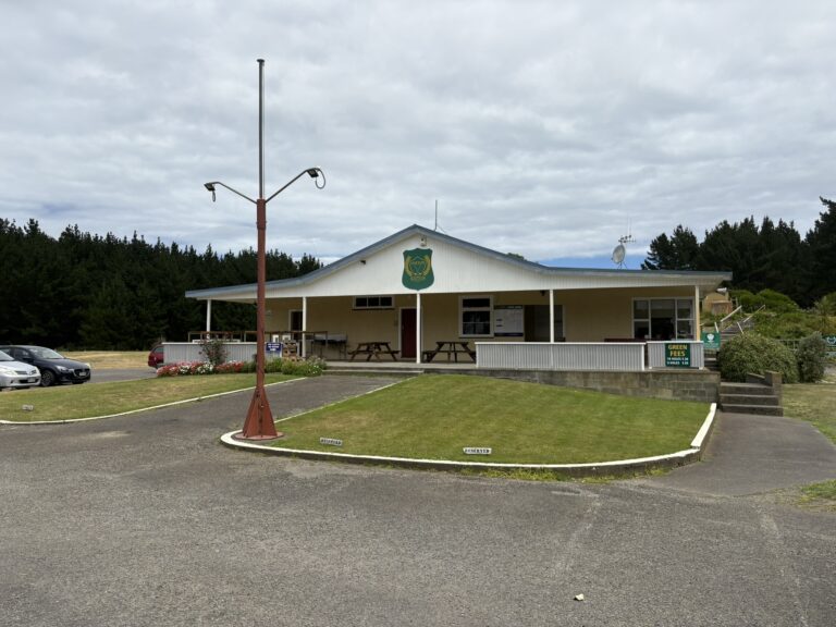 Foxton Golf Club clubhouse with veranda, green fees sign and lawn under cloudy sky