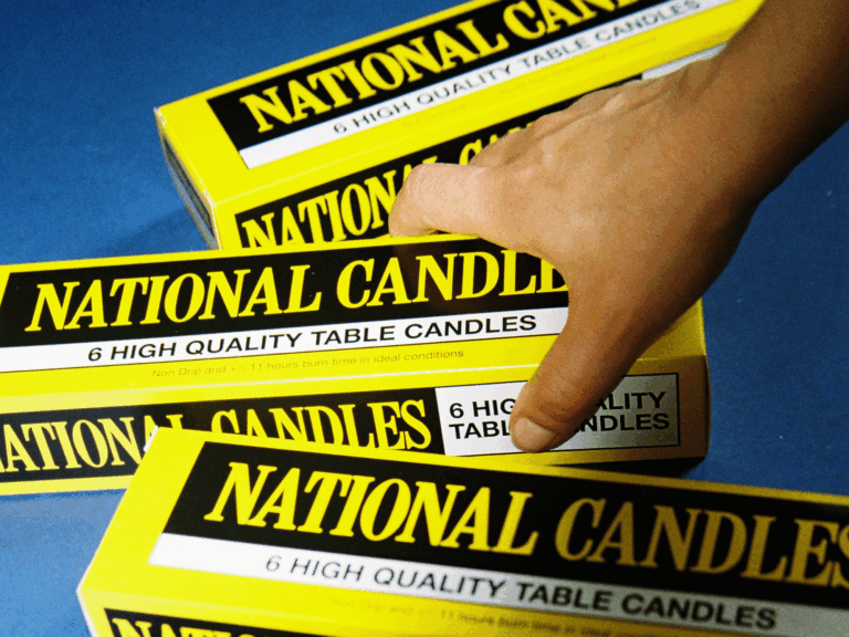 Hand picking up a yellow National Candles box of six table candles